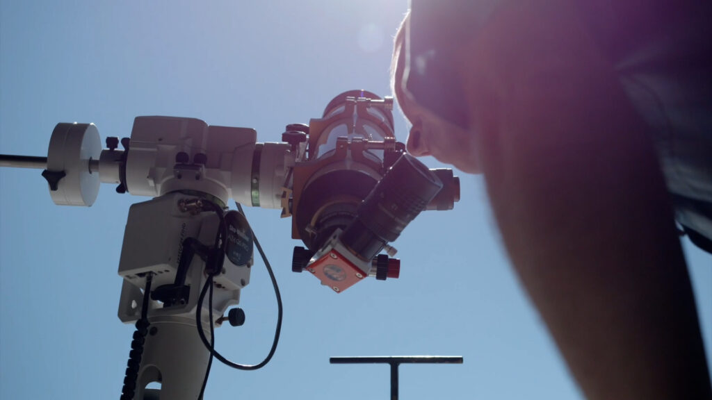 A person looking through a solar telescope