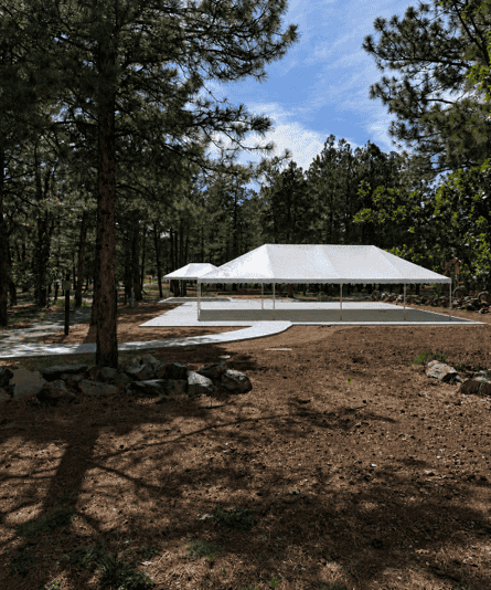 Outdoor event tent at Lowell Observatory surrounded by pine trees in Flagstaff, Arizona.