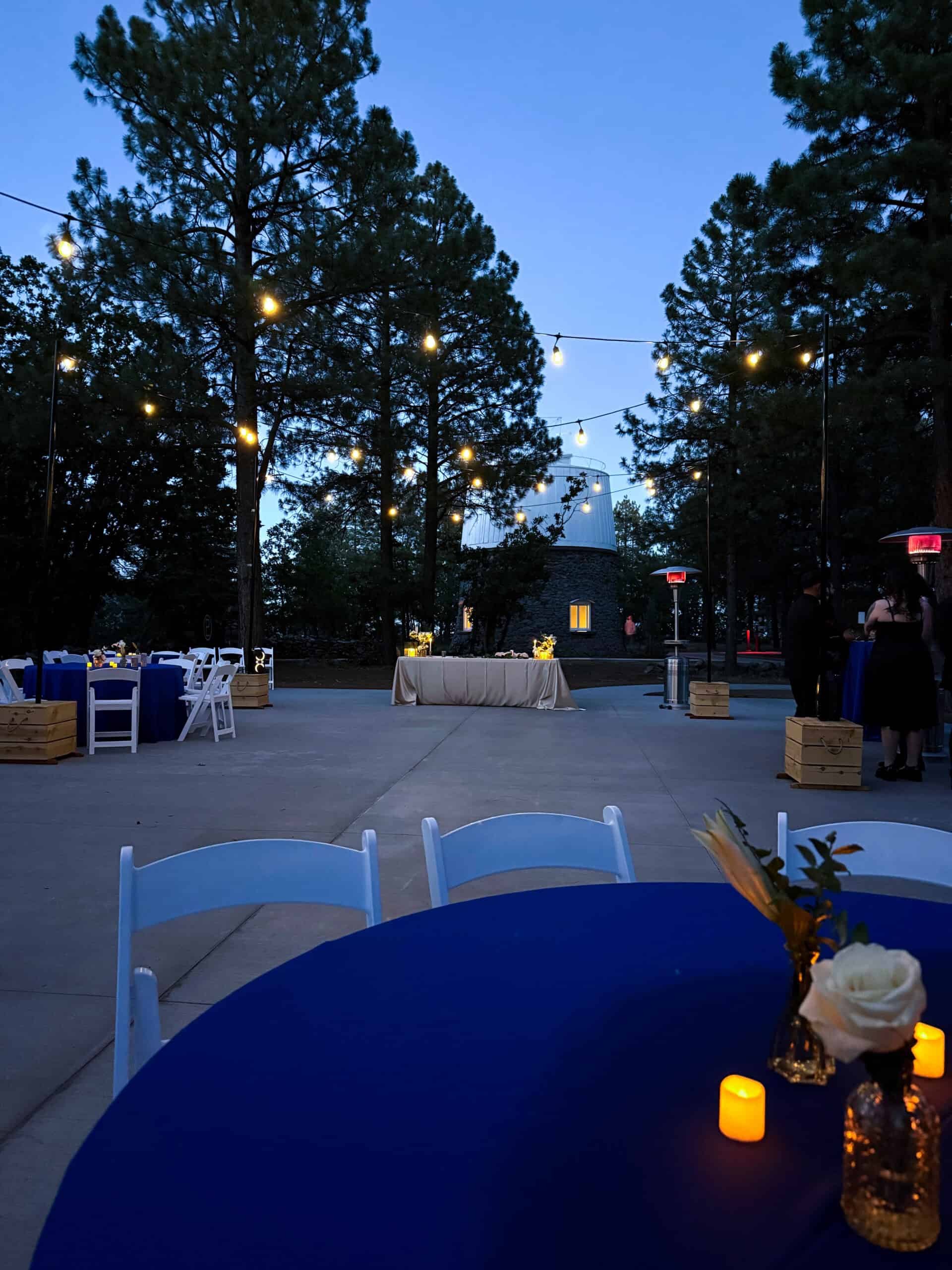 Outdoor event at Lowell Observatory with string lights, tables, and chairs.